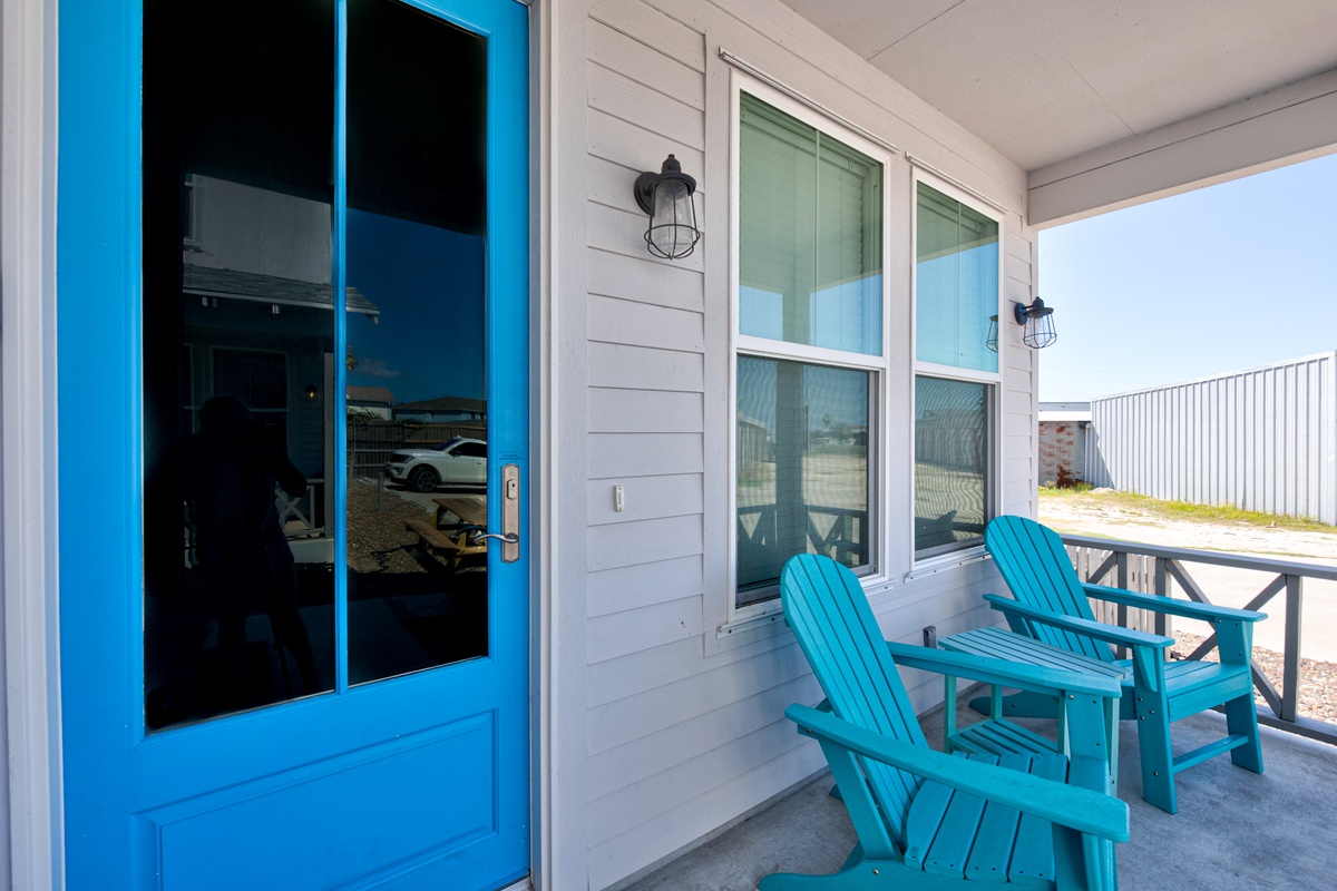 Your private covered porch offers a relaxing retreat with bright blue Adirondack chairs perfect for morning coffee or evening conversations.