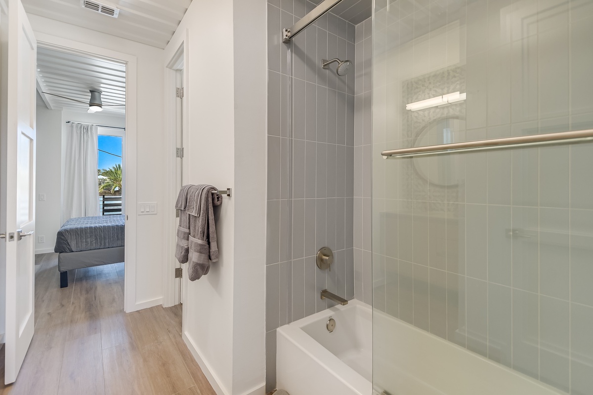 Refresh in your spacious modern bathroom with rainfall shower, sleek gray tiles, and fluffy towels waiting for you.