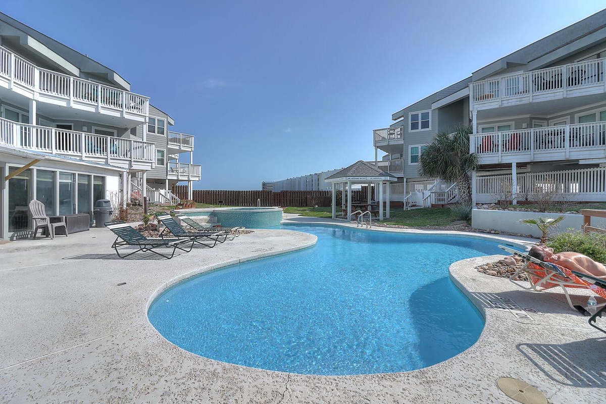 Beautiful resort-style pool with multiple levels surrounded by well-maintained multi-story buildings featuring private balconies and tropical landscaping.