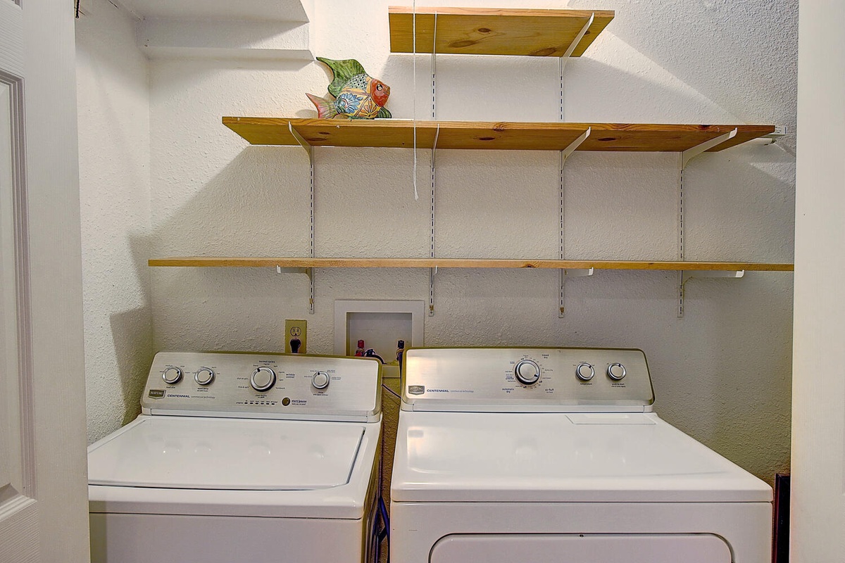 Your laundry needs are handled with this convenient washer and dryer setup, complete with wooden shelving for your supplies.