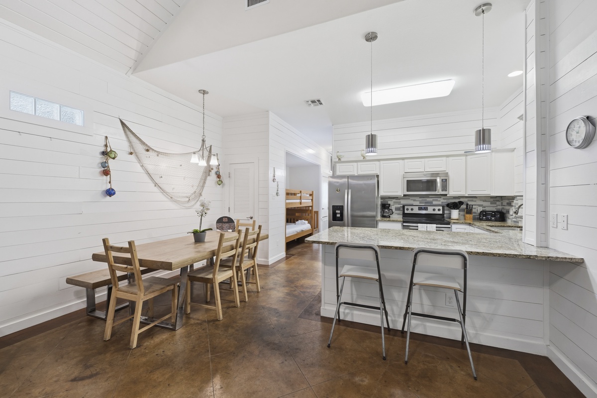 Gather around the rustic dining table or perch at the modern breakfast bar in this bright, spacious kitchen. Vaulted ceilings and coastal touches create a warm, inviting space for shared meals.