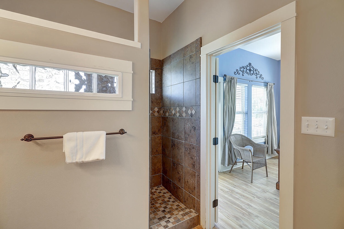 Step into your spa-like bathroom featuring an elegant tiled walk-in shower with natural light streaming through the window.