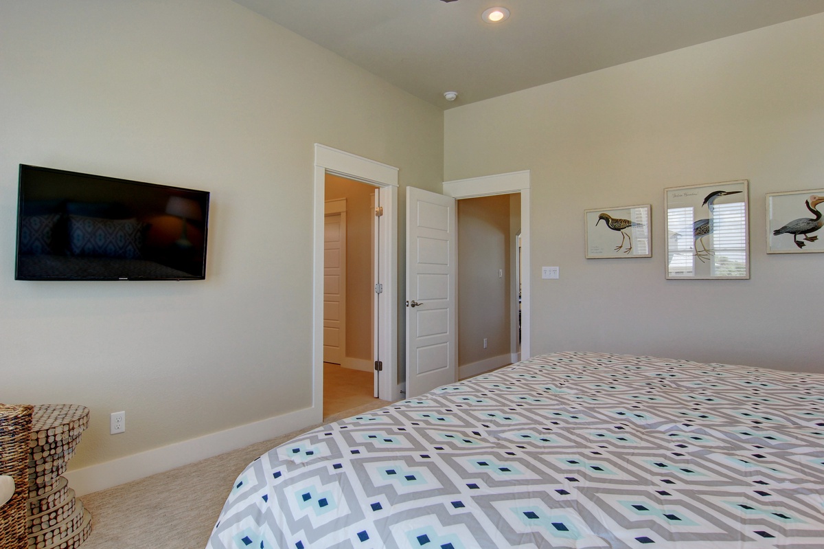 Your peaceful bedroom features a comfortable king bed, flat-screen TV, and charming bird artwork creating a serene coastal retreat.