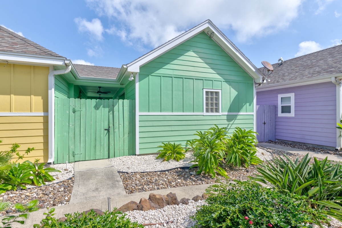 Charming colorful cottages create a vibrant village atmosphere with lush tropical landscaping and coastal architectural details.