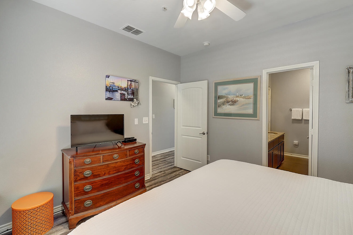 Drift into comfort in your serene bedroom featuring a ceiling fan, cozy seating, and convenient en-suite access.