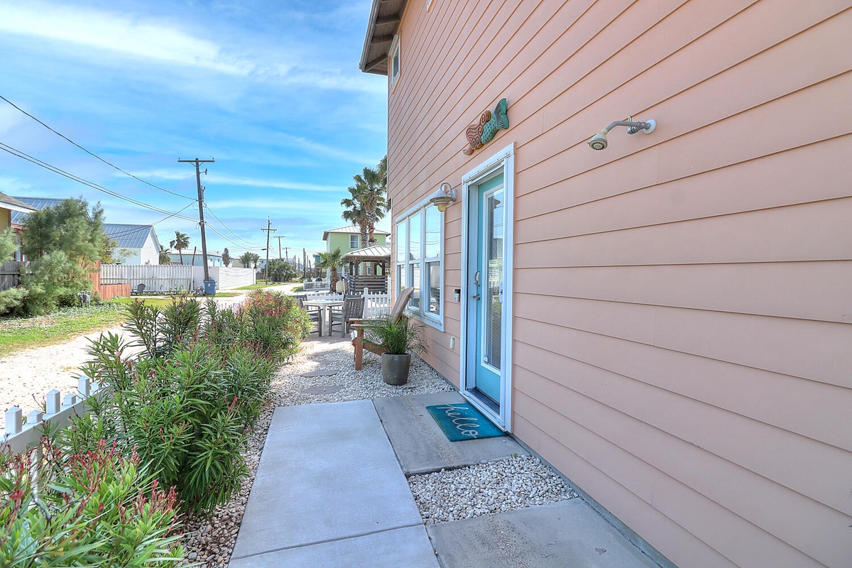 Charming coastal entrance with tropical landscaping and welcoming turquoise door sets the perfect beach vacation mood.