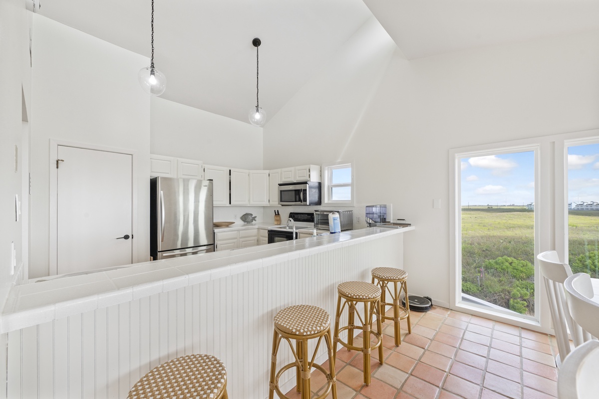 Gather around your bright breakfast bar while natural light pours through windows showcasing peaceful marsh views.