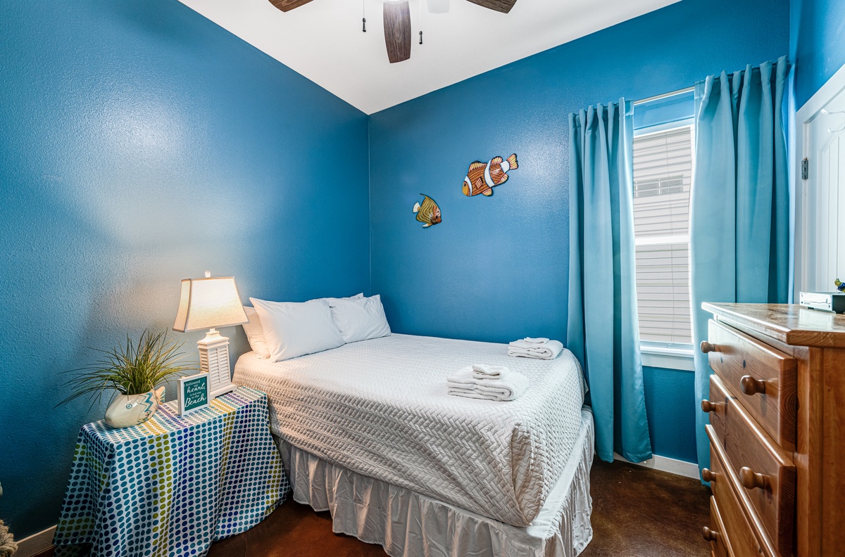 Drift off peacefully in this ocean-themed bedroom, where vibrant blue walls and playful fish decorations create your own underwater sanctuary.