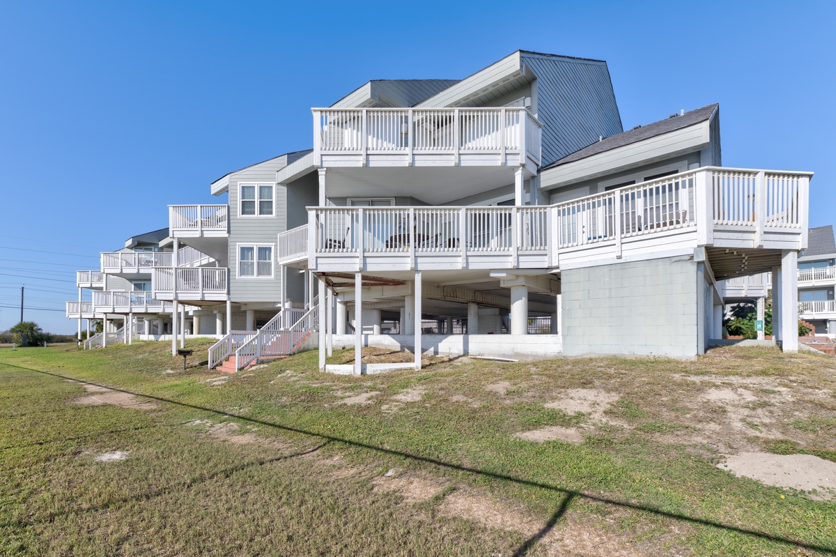 Modern beachfront property featuring multiple levels and spacious balconies under clear blue skies.