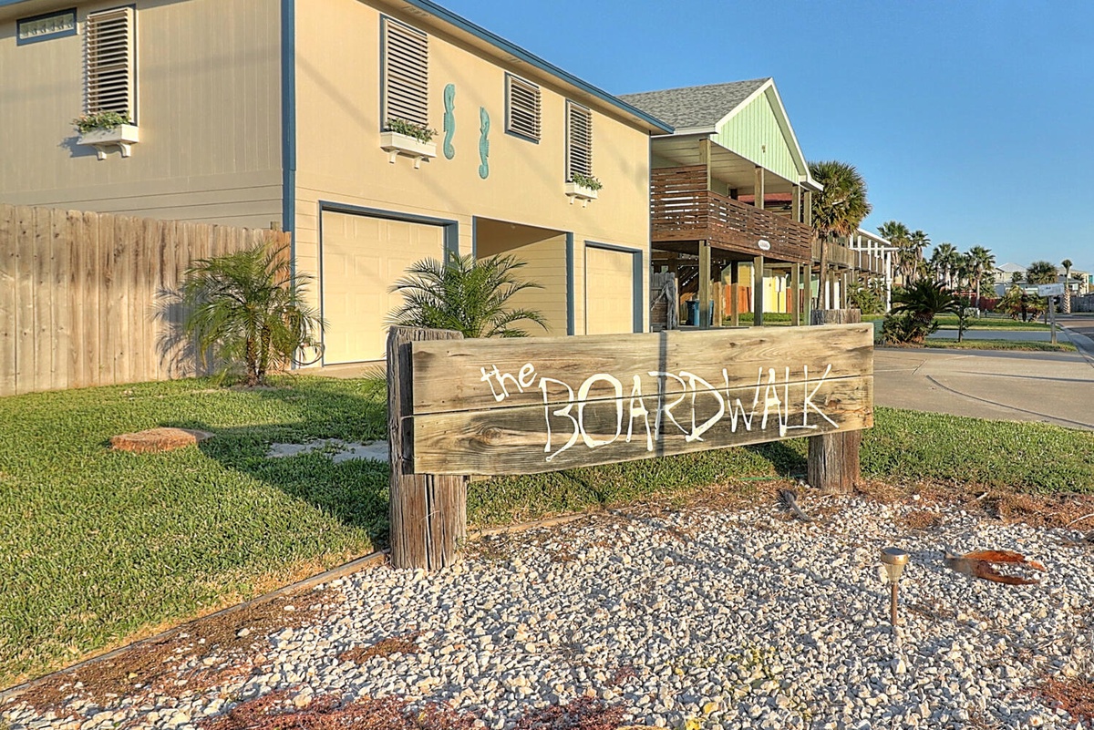 The Boardwalk welcomes guests to a charming coastal community with colorful beach-style buildings and palm trees.