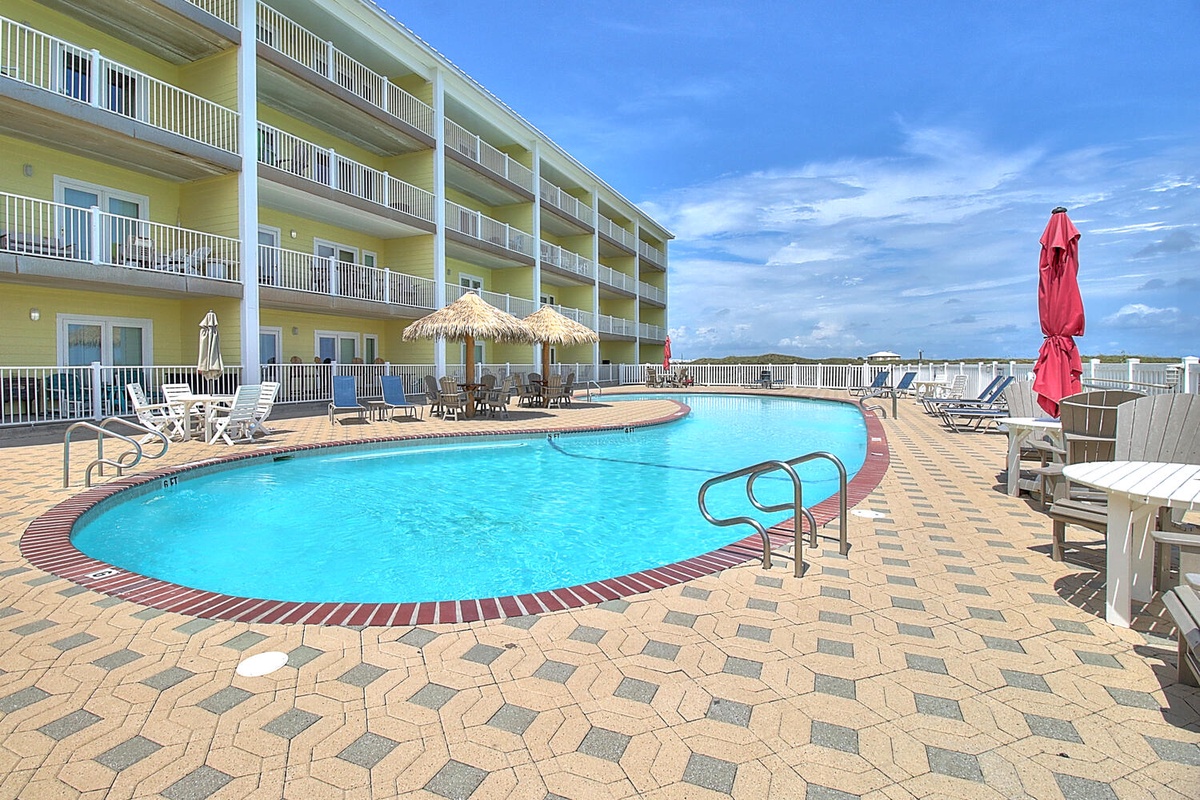 Sparkling pool deck with tropical umbrellas and loungers awaits your perfect beach vacation getaway.