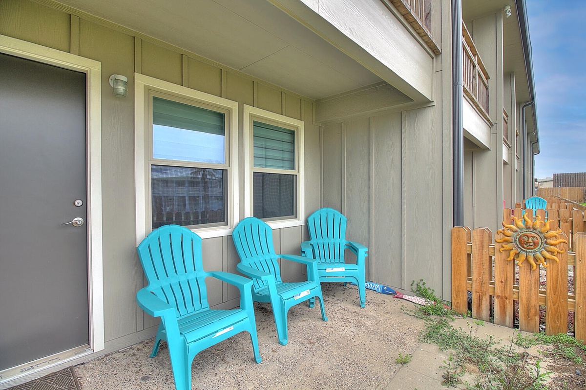 Relax on your private patio with bright turquoise chairs, perfect for morning coffee or evening conversations under the covered space.