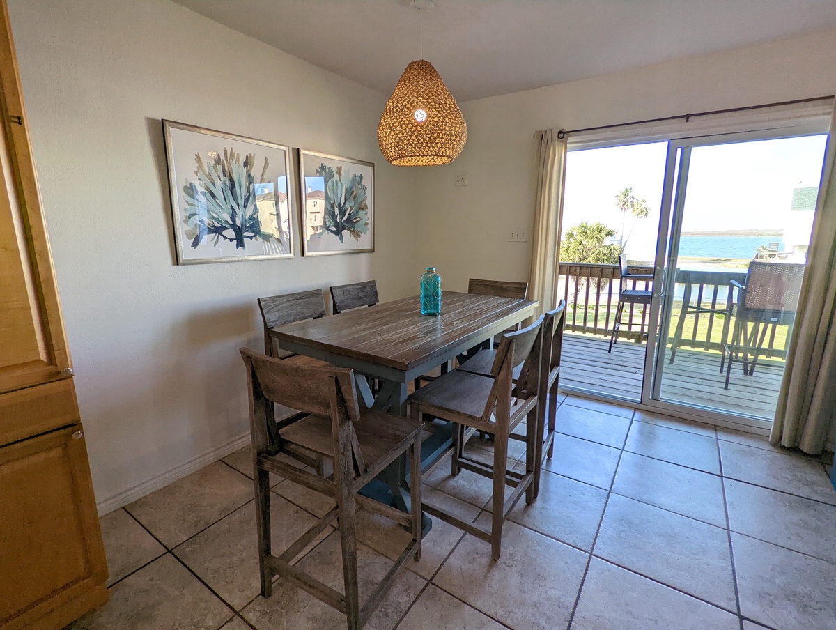 Your bright dining space opens to stunning ocean views, where coastal artwork and woven lighting create perfect ambiance for memorable meals.