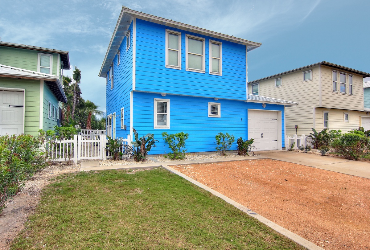 Bright blue coastal home with convenient parking and charming landscaped surroundings in a peaceful residential neighborhood.