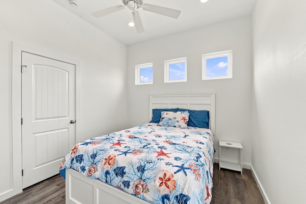 Your coastal second bedroom awaits with vaulted ceilings, a ceiling fan for comfort, and three bright windows flooding the space with natural light.
