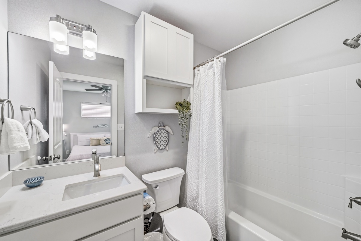 Freshen up in your bright, modern bathroom with soft lighting, storage above the toilet, and a cheerful turtle accent. Everything you need is within arm's reach.