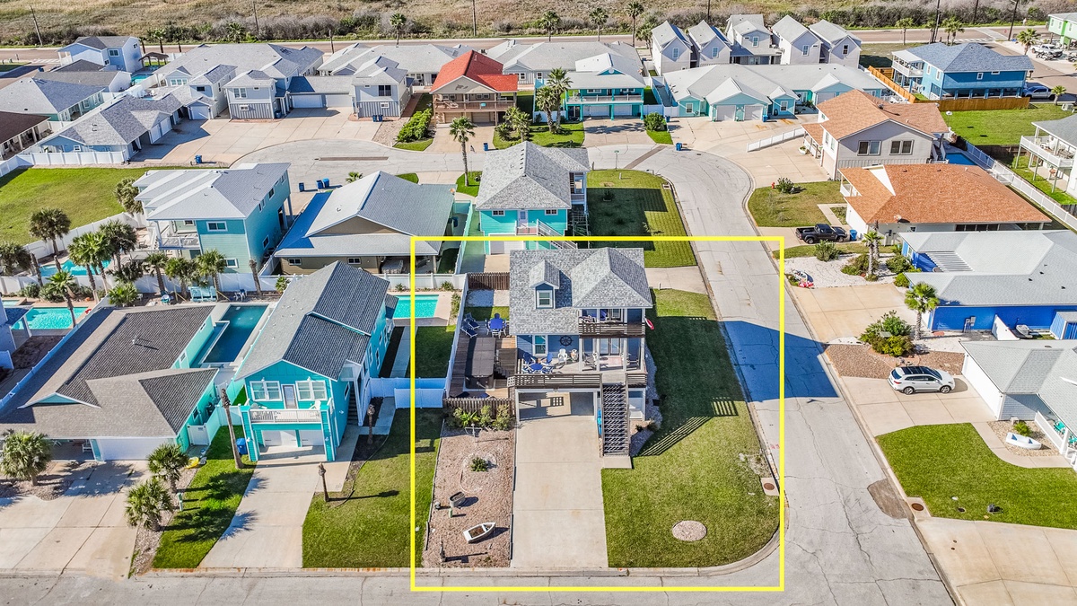 Aerial view of a vibrant coastal neighborhood with colorful beach houses and well-maintained yards.
