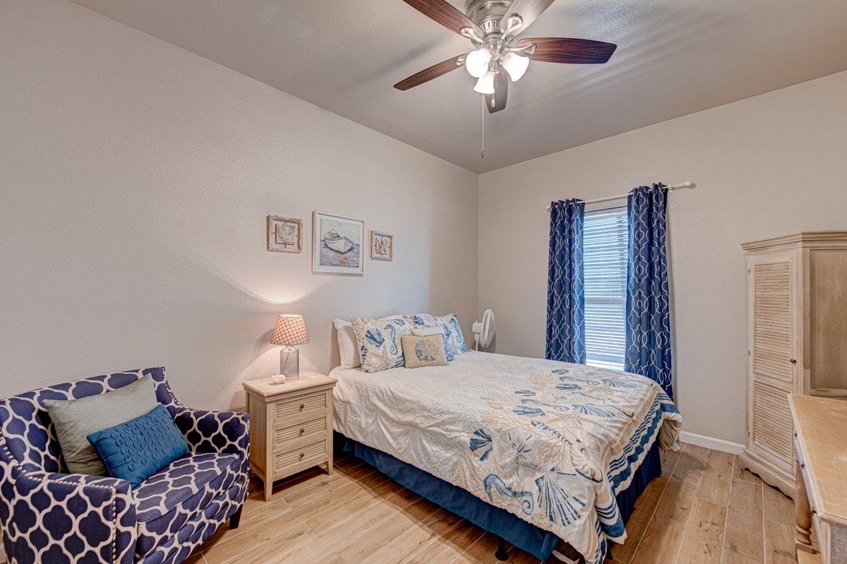Rest peacefully in this coastal-themed bedroom with nautical touches, comfortable seating, and refreshing ceiling fan for perfect sleeping comfort.