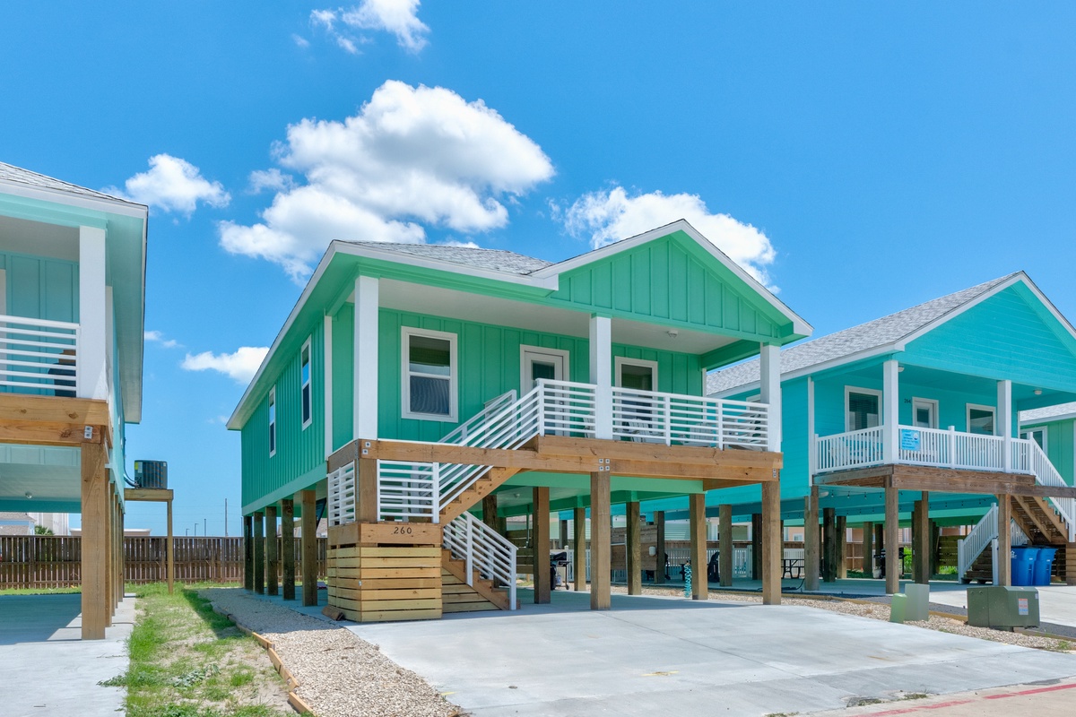 Vibrant coastal homes with elevated design feature modern comfort and beachside charm under brilliant blue skies.