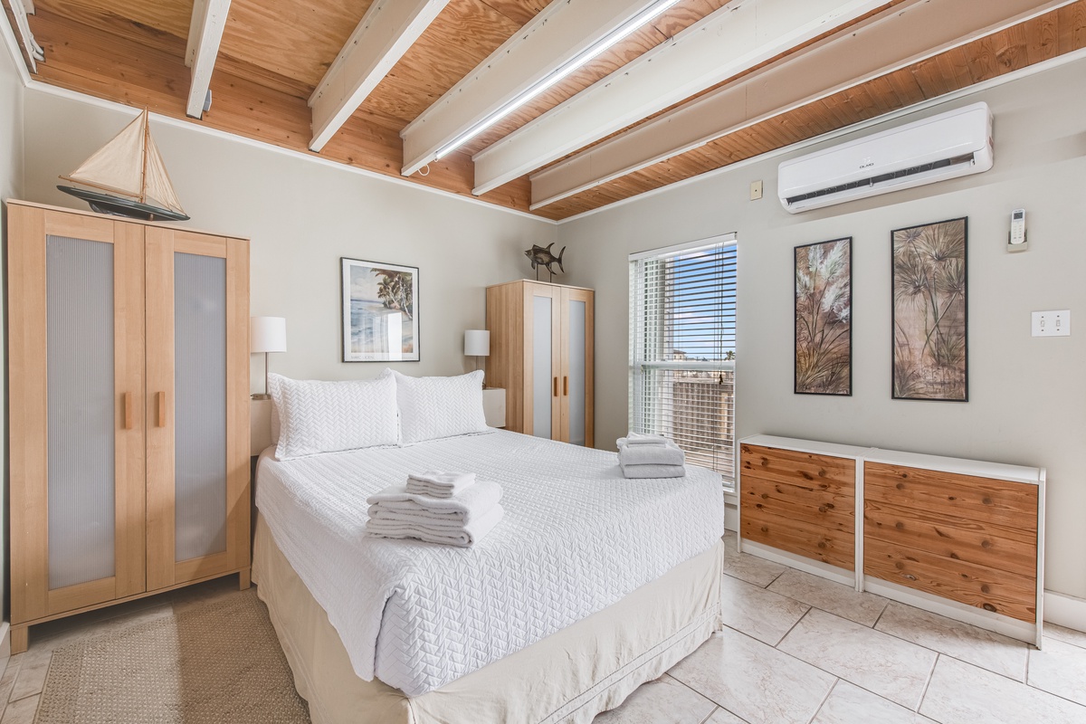 Relax in your serene bedroom with exposed wooden beams, crisp linens, and cool air conditioning for perfect comfort.
