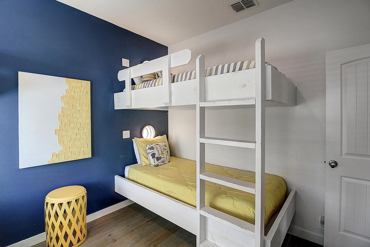 Your kids will love this cheerful bunk room with sunny yellow bedding and fun geometric artwork against a vibrant blue accent wall.