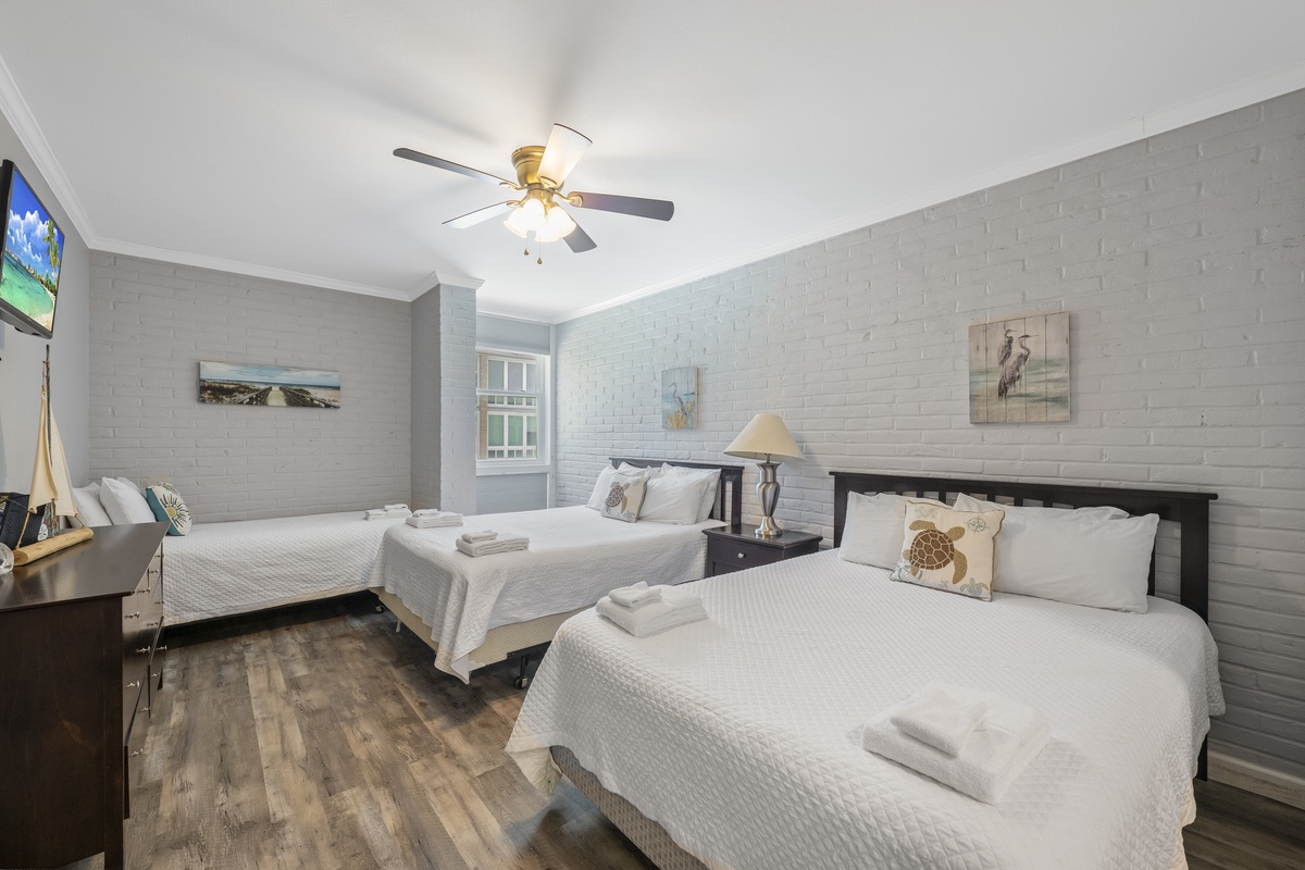 Relax in your spacious twin bedroom with coastal charm, featuring comfortable beds, ceiling fan, and thoughtful amenities for a perfect stay.