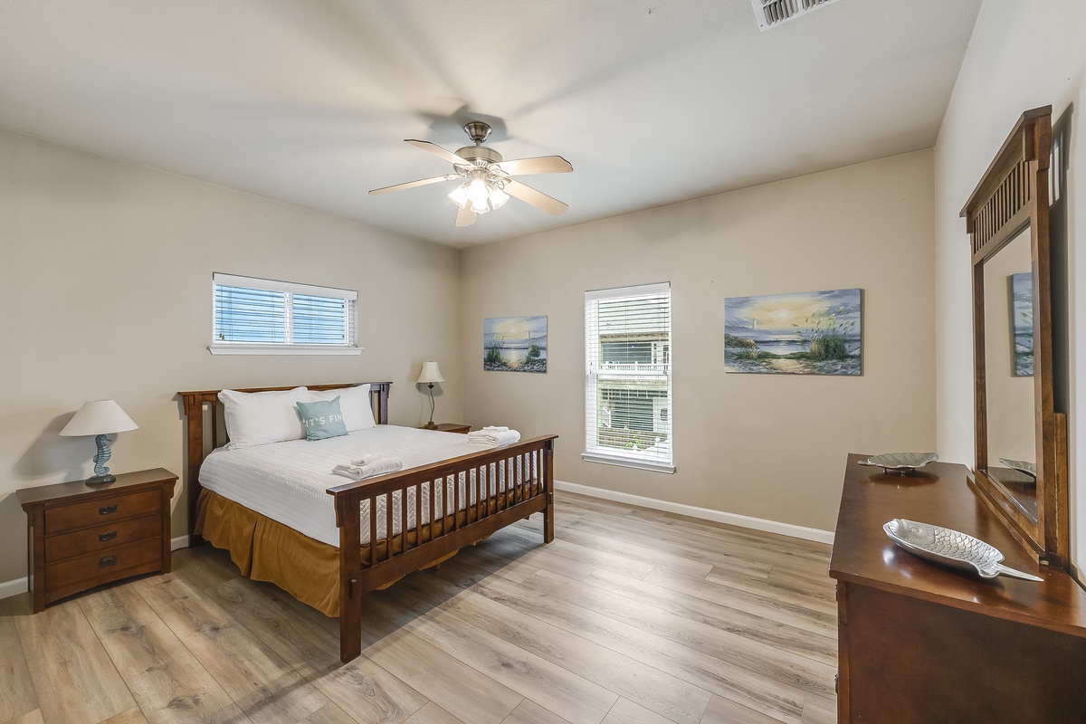 Rest peacefully in your inviting bedroom with coastal artwork and warm wood furnishings creating a serene retreat.