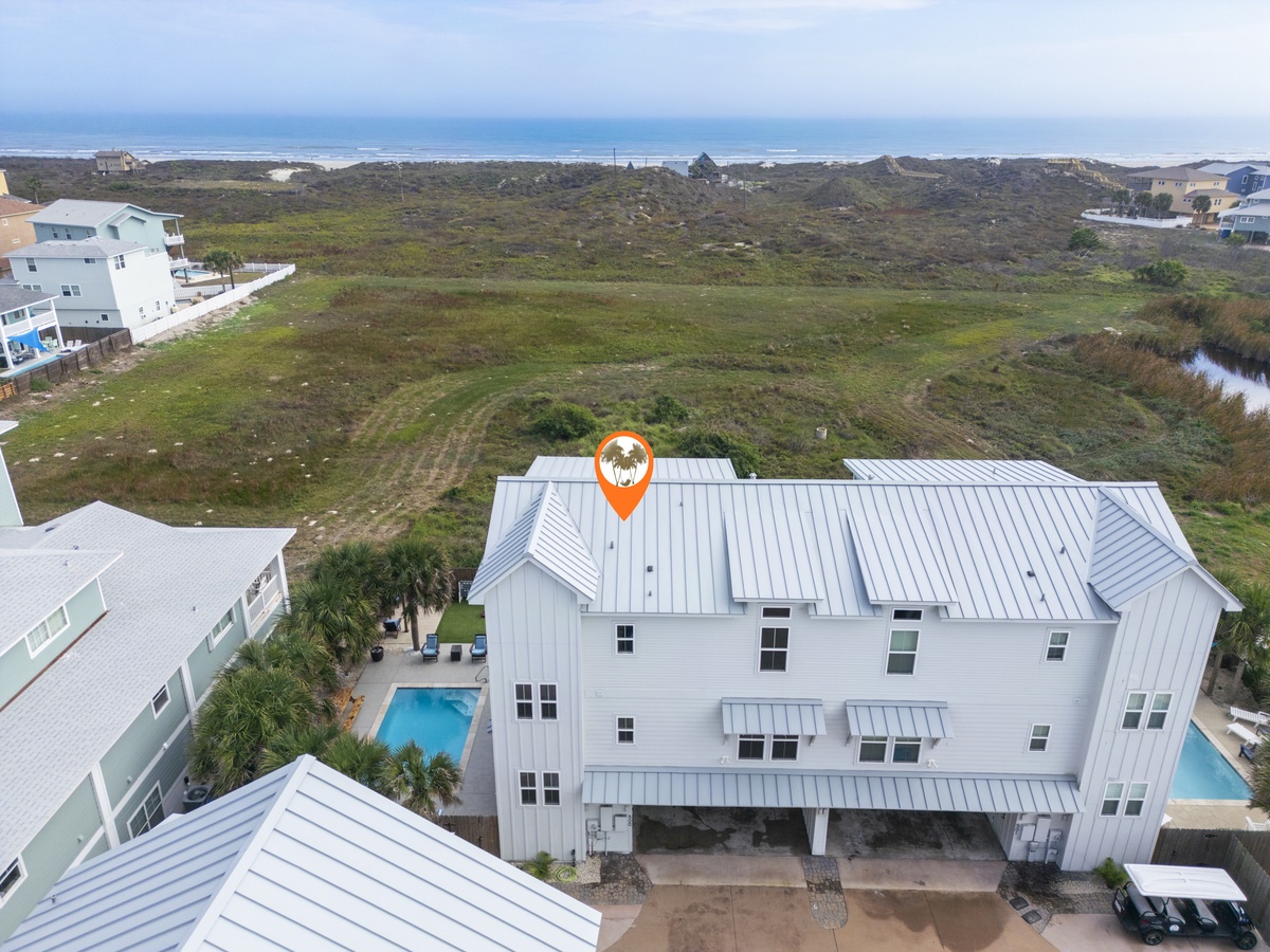 Aerial view of coastal vacation rental featuring private pool, beachfront location with dune access, and nearby oceanfront properties.