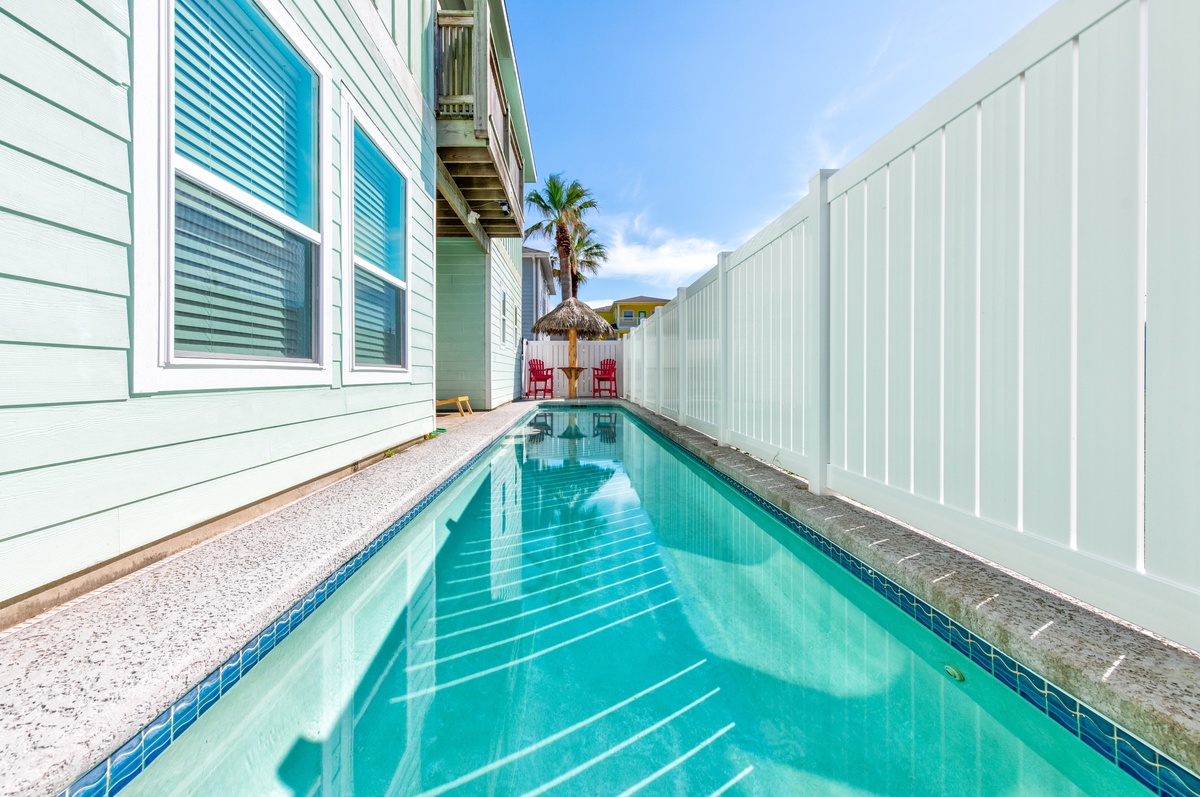 Your own tropical oasis awaits with crystal-clear pool waters reflecting palm trees and bright blue skies above.