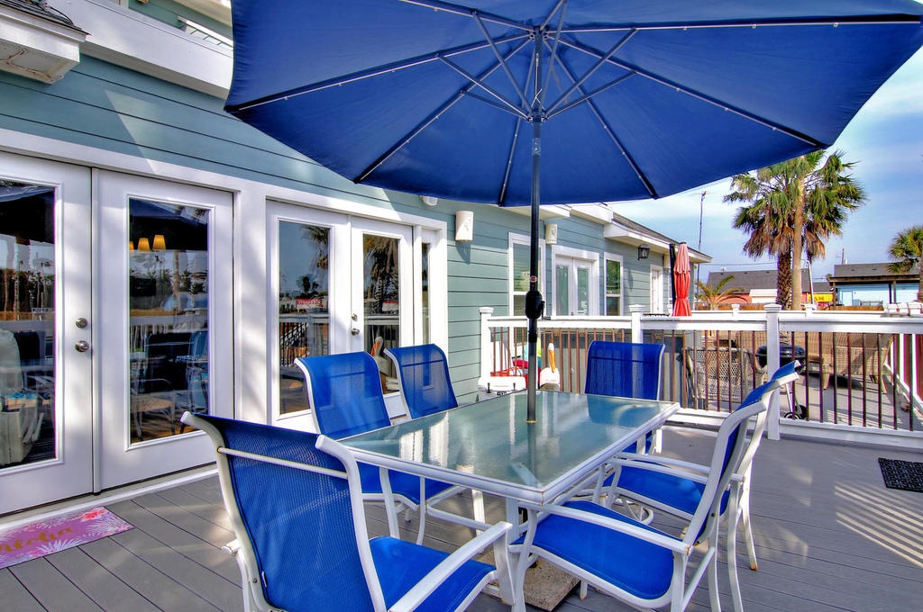 Gather around your private patio table for meals under the coastal sun, with a blue umbrella providing perfect shade.