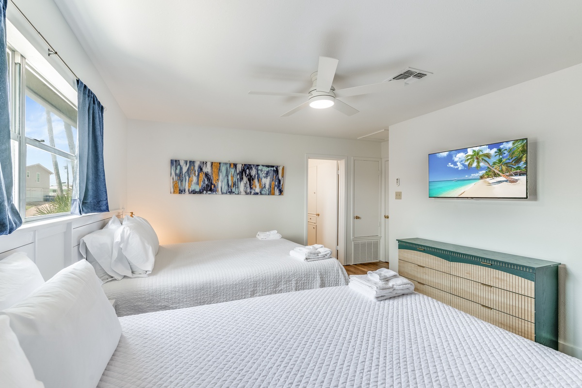 Drift into peaceful sleep in your bright guest room, complete with twin beds, tropical artwork, and modern TV for ultimate relaxation.