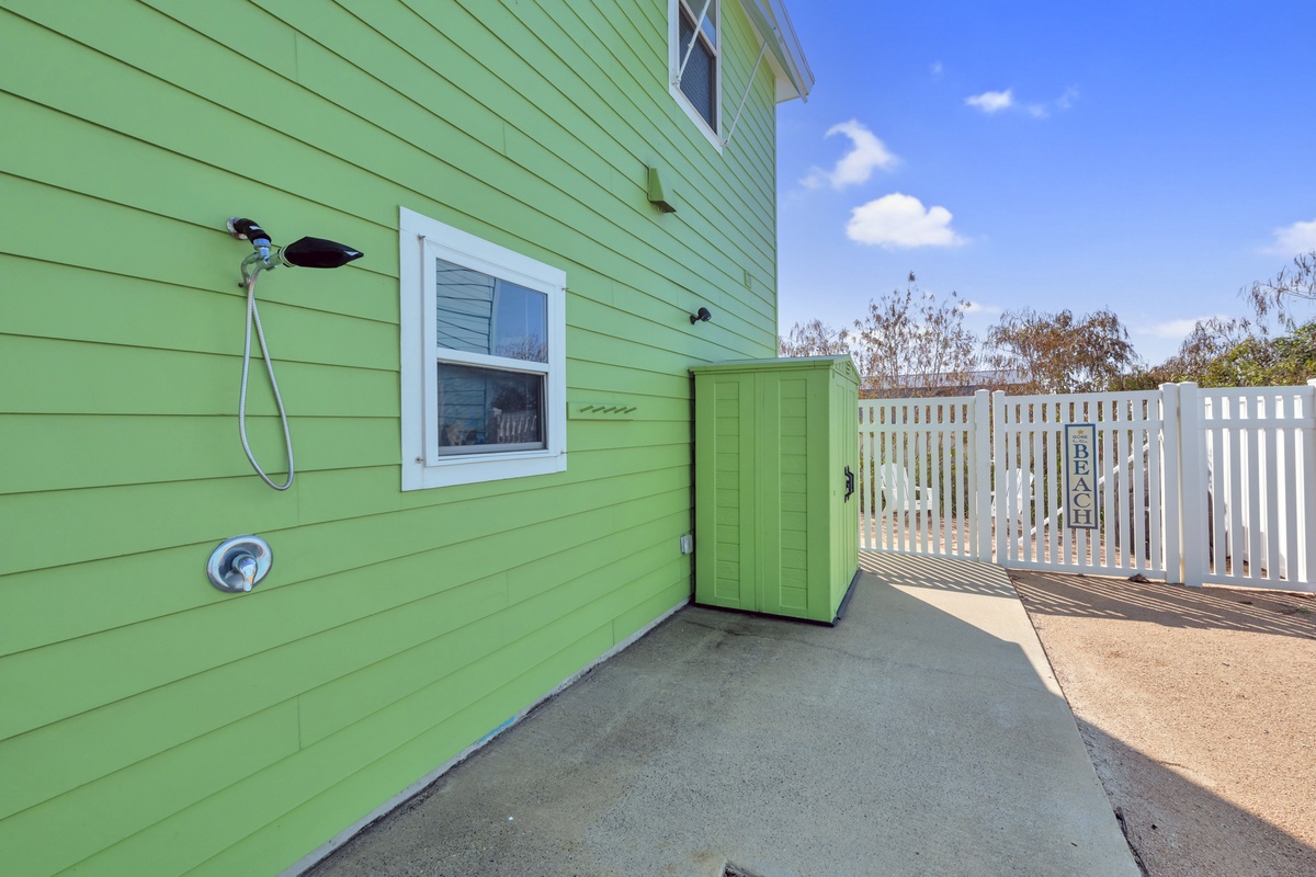 This charming green property features convenient outdoor shower facilities perfect for rinsing off after beach days or outdoor adventures.
