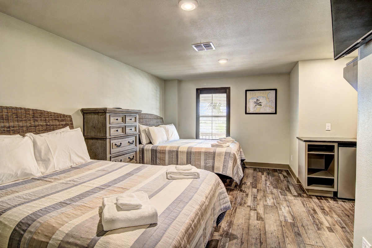 Unwind in this cozy twin bedroom with rustic charm, where plaid bedding and warm wood floors create your peaceful retreat.