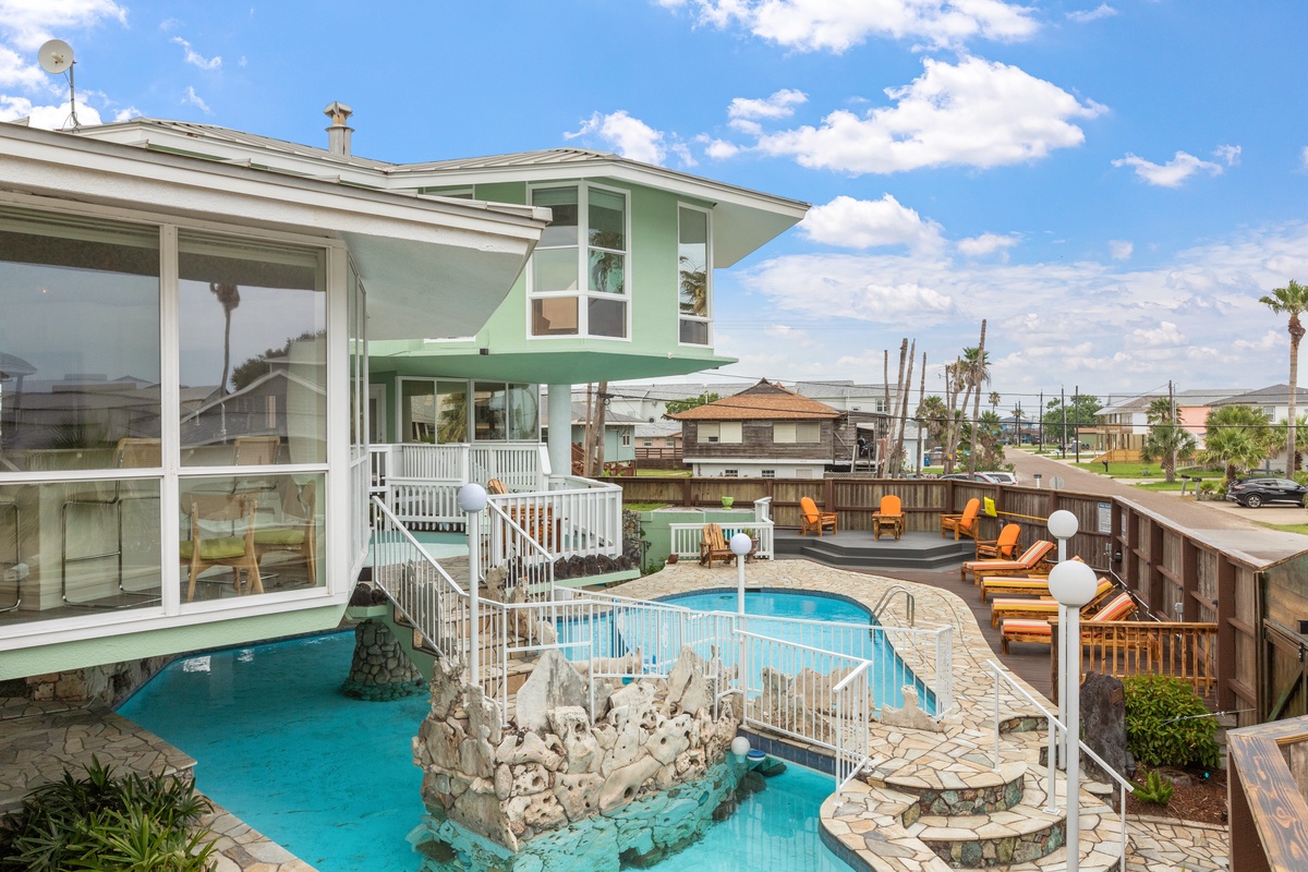 Multi-level vacation home featuring a stunning lagoon-style pool with rock formations and tropical outdoor deck seating area.