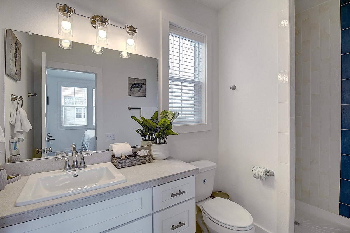 Step into your bright, modern bathroom with fresh white cabinets, elegant vanity lighting, and thoughtful touches like a greenery basket to make you feel at home.