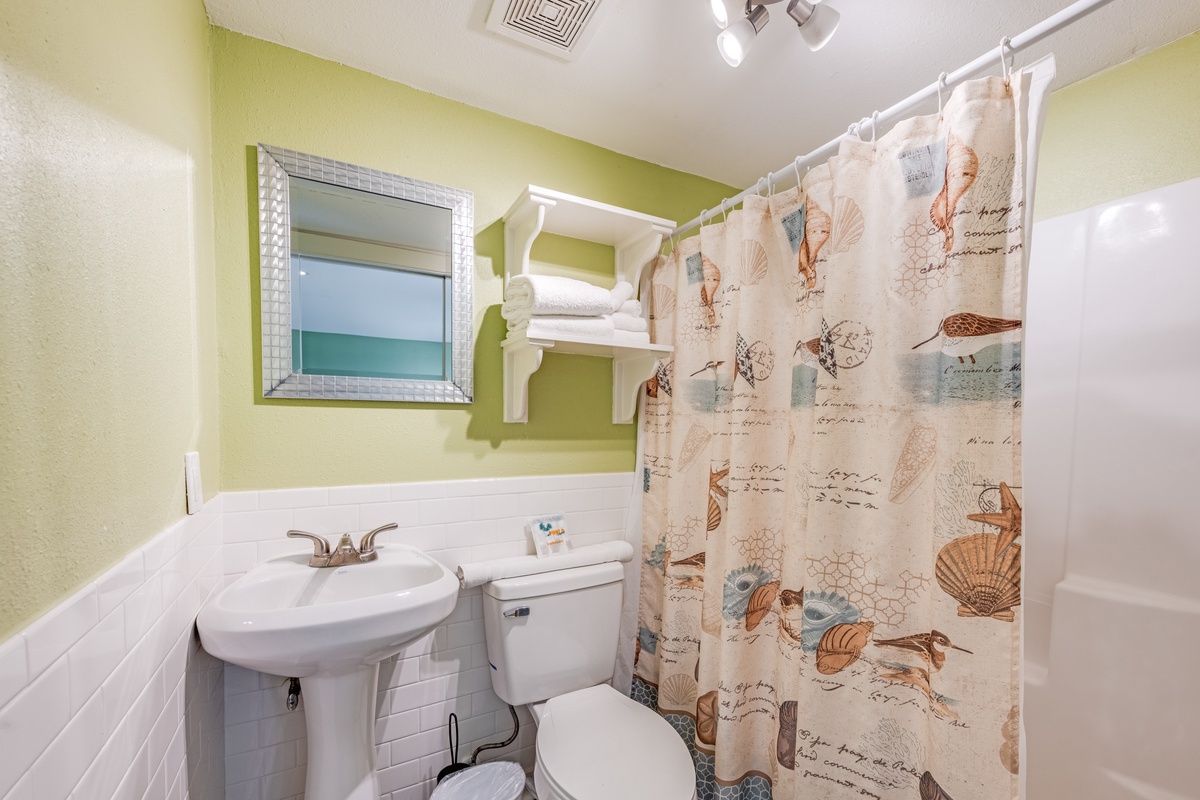 Refresh in your private bathroom featuring a charming seashell-themed shower curtain and cheerful green walls that brighten your morning routine.