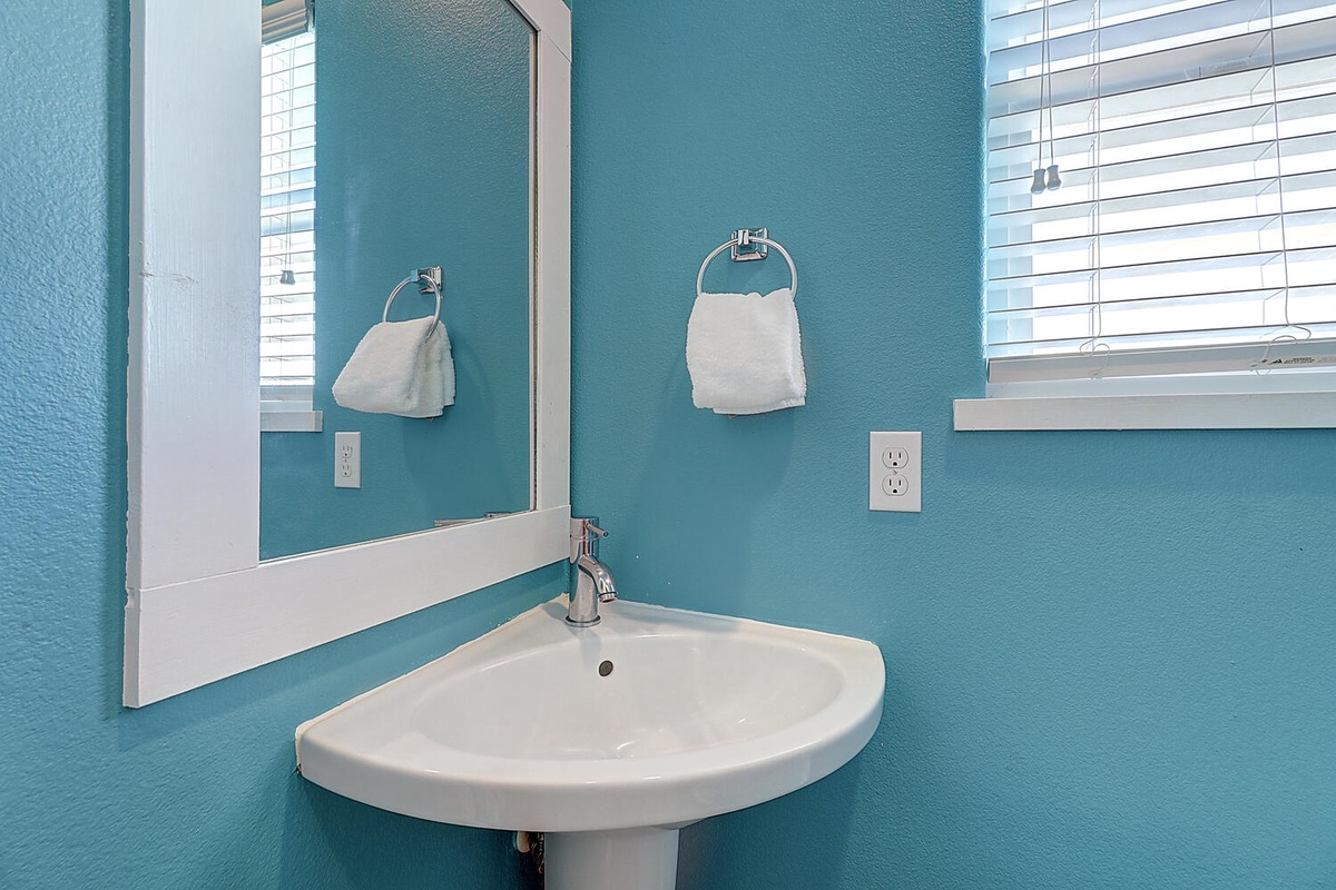 Freshen up in your bright, cheerful bathroom with ocean-inspired teal walls and a stylish corner sink that maximizes your space perfectly.