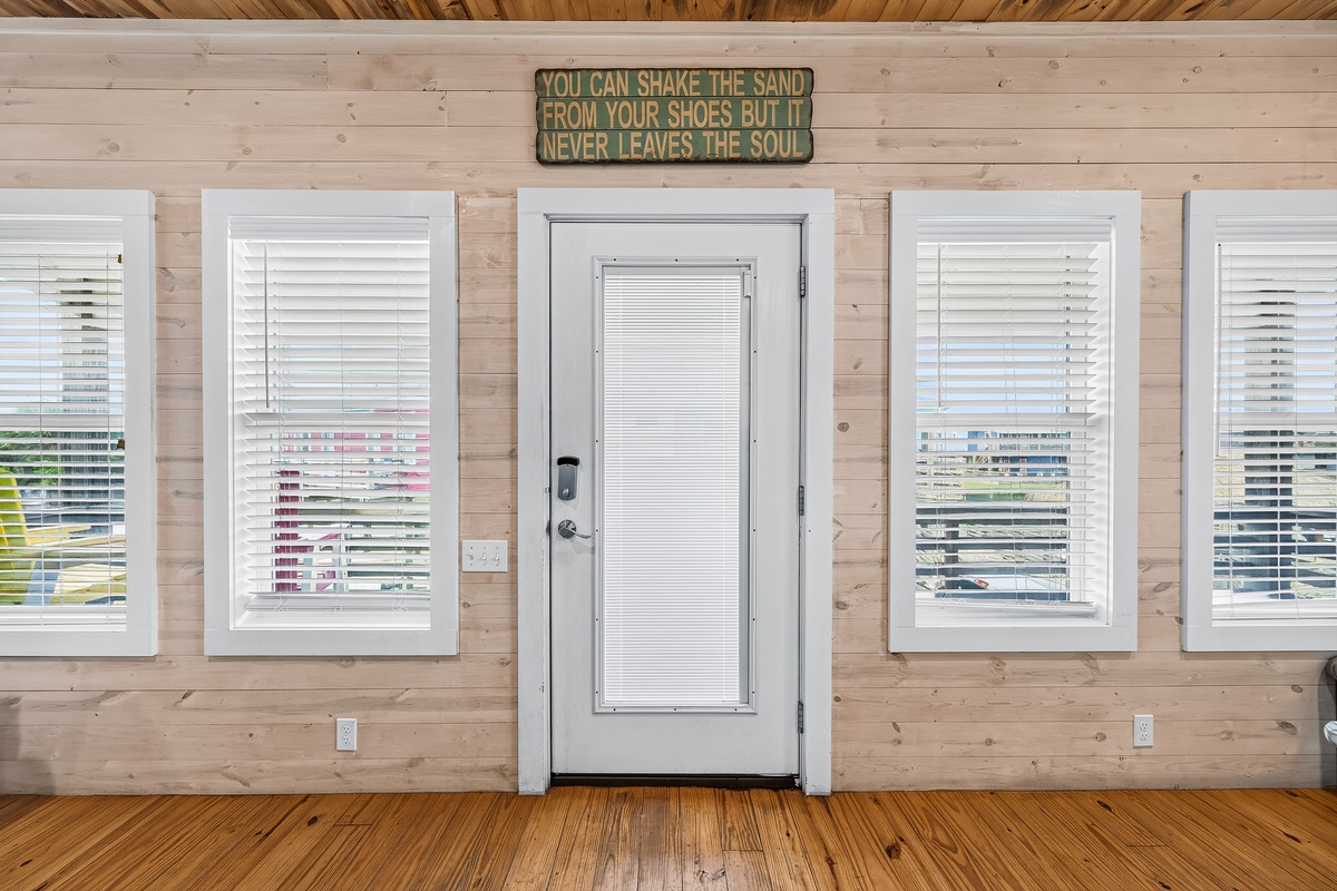 Charming coastal-inspired entryway welcomes you with warm wood paneling, bright natural light, and beach-themed décor that sets the tone for your relaxing getaway.