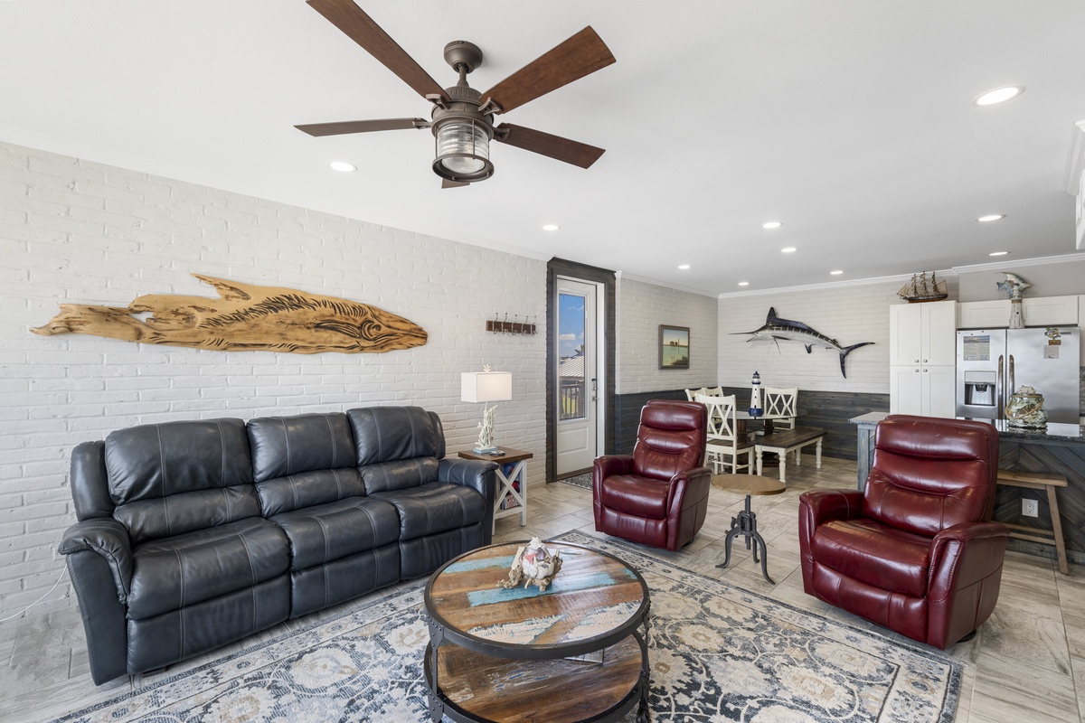 Relax in your nautical-themed living room with leather seating, coastal artwork, and a ceiling fan keeping you cool.
