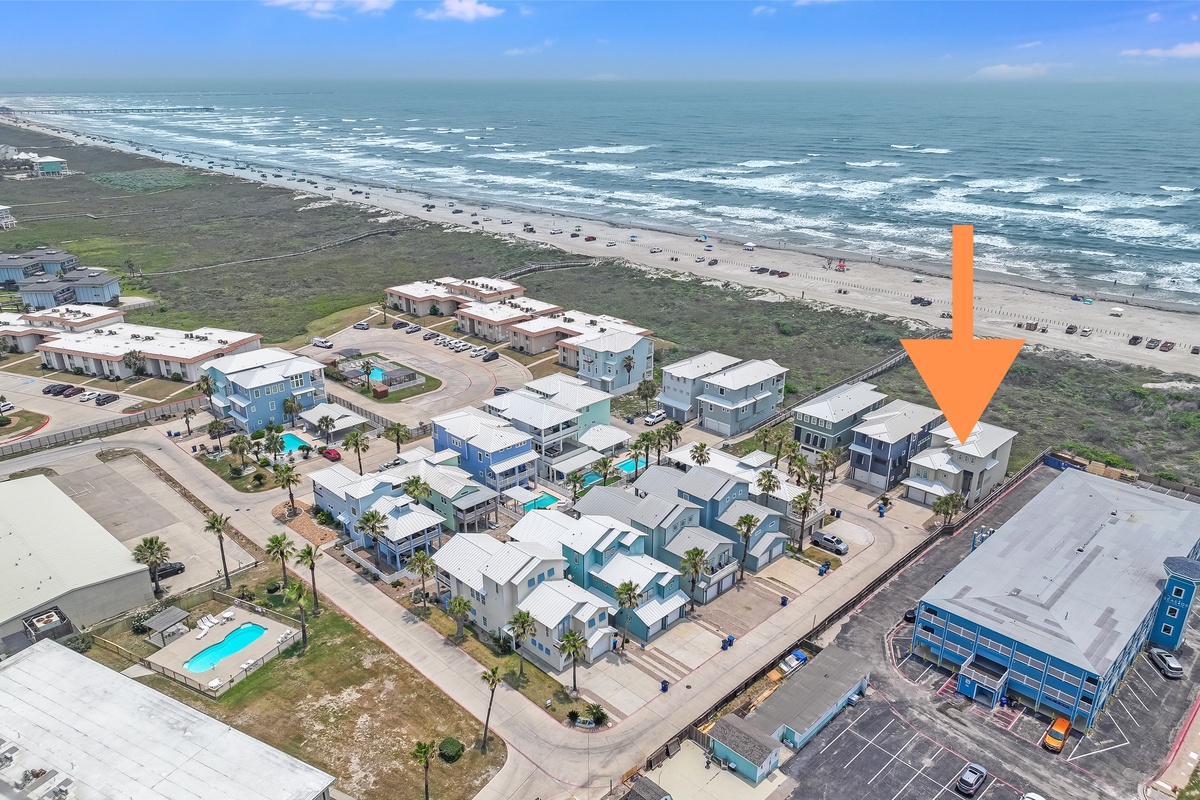 Aerial view of beachfront property development just steps from pristine sandy shores and rolling ocean waves.