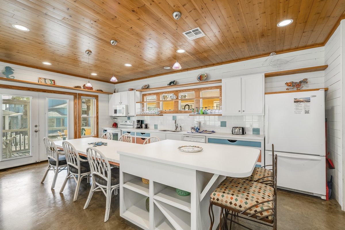 Gather around your spacious kitchen island where wood ceilings and coastal charm create the perfect setting for morning coffee and evening meals together.