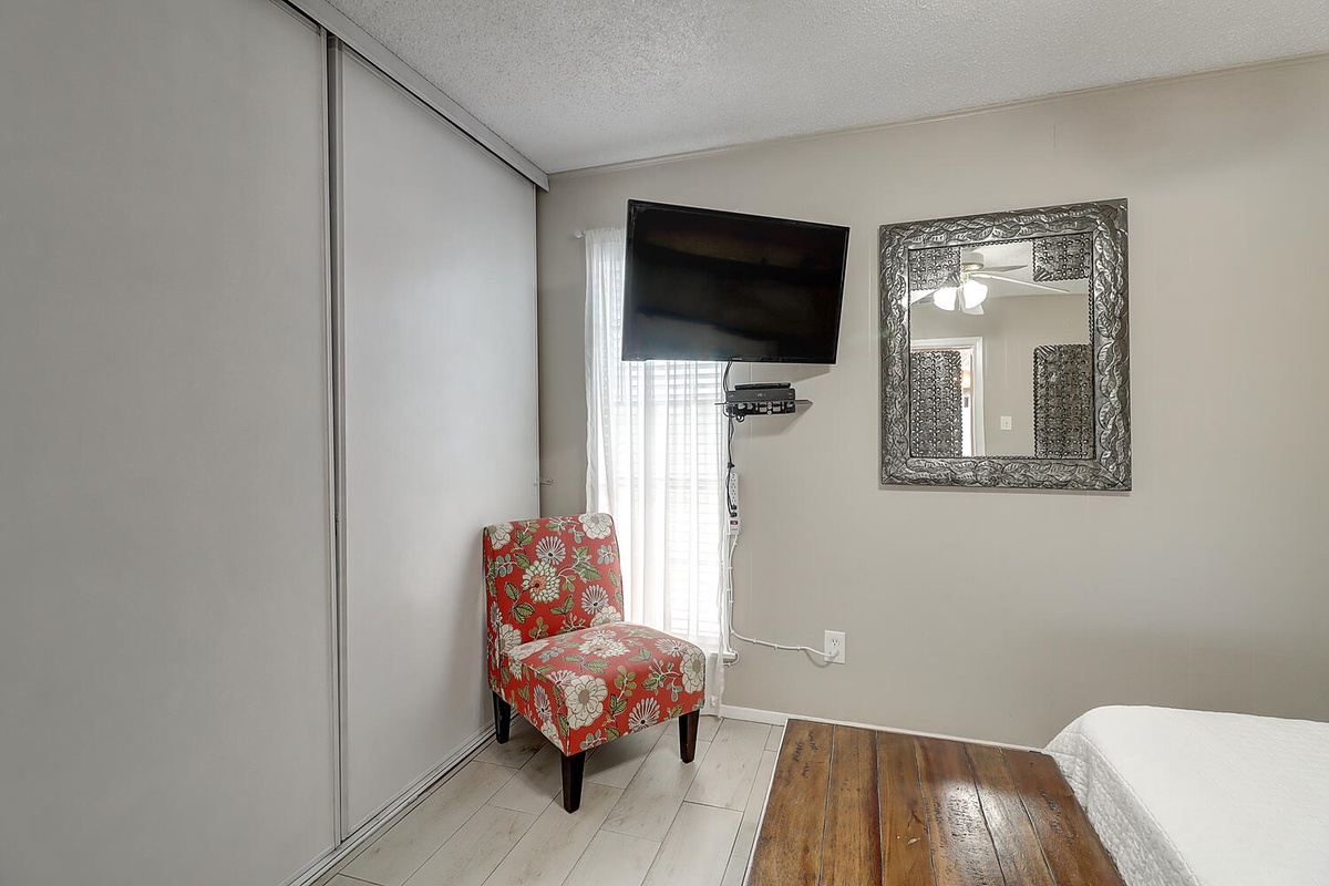 Relax in your cozy reading nook with a vibrant floral chair while enjoying entertainment on the wall-mounted TV.
