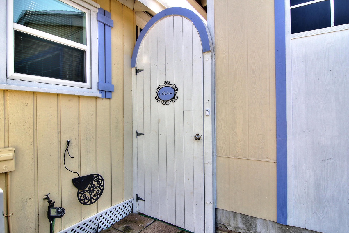 A charming arched door with coastal blue trim marks your private entrance, featuring decorative details that welcome you home.