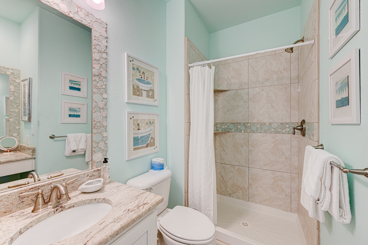 Refresh in your spa-inspired bathroom with soothing mint walls, marble accents, and a spacious walk-in shower perfect for unwinding after beach adventures.