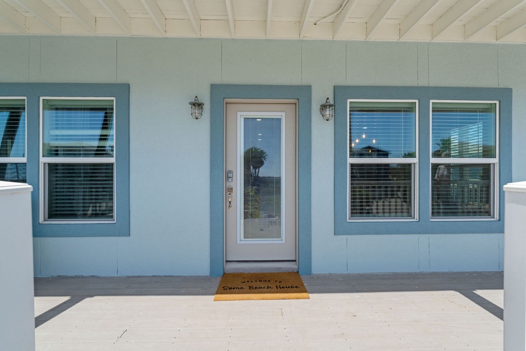Charming blue beach house entrance with welcoming front door and coastal-style covered porch area.