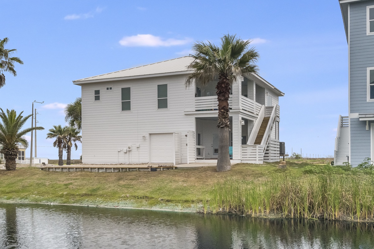 Coastal vacation home with palm trees and waterfront access in a peaceful neighborhood setting.