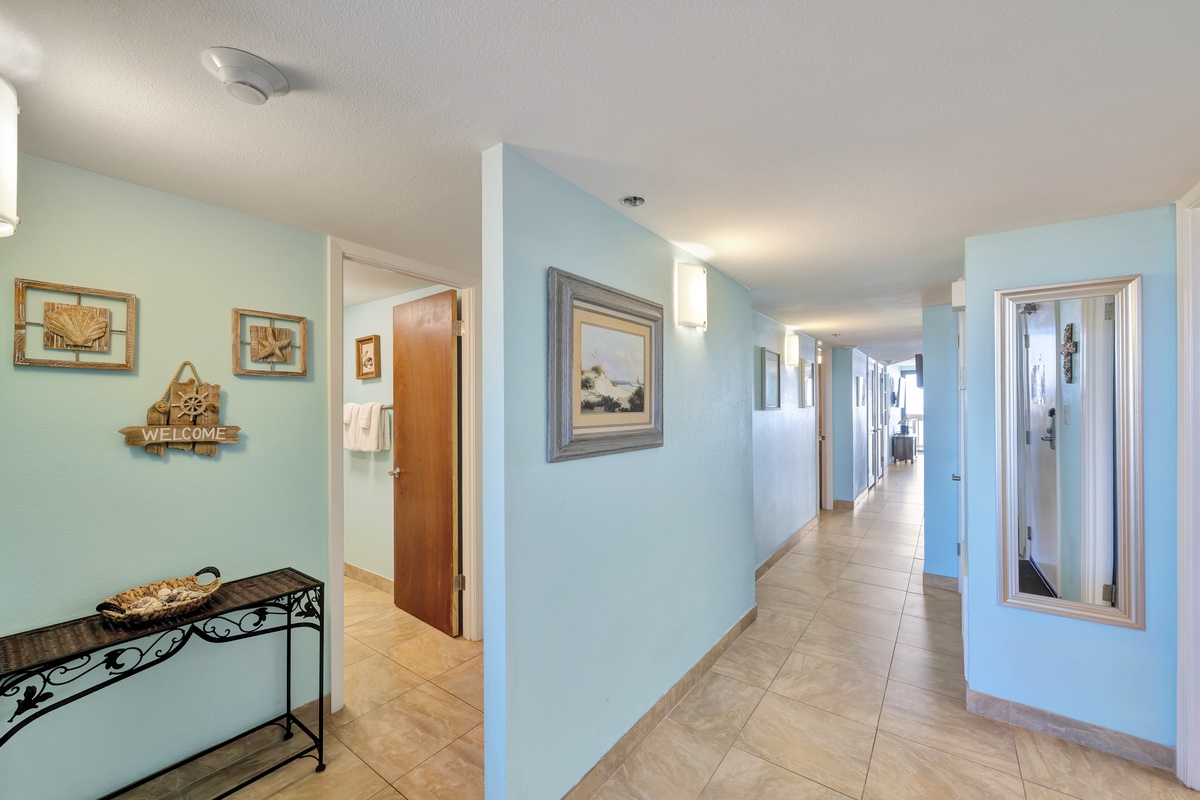 Step into your coastal retreat where soothing blue walls and nautical touches create a welcoming atmosphere throughout the spacious hallway.