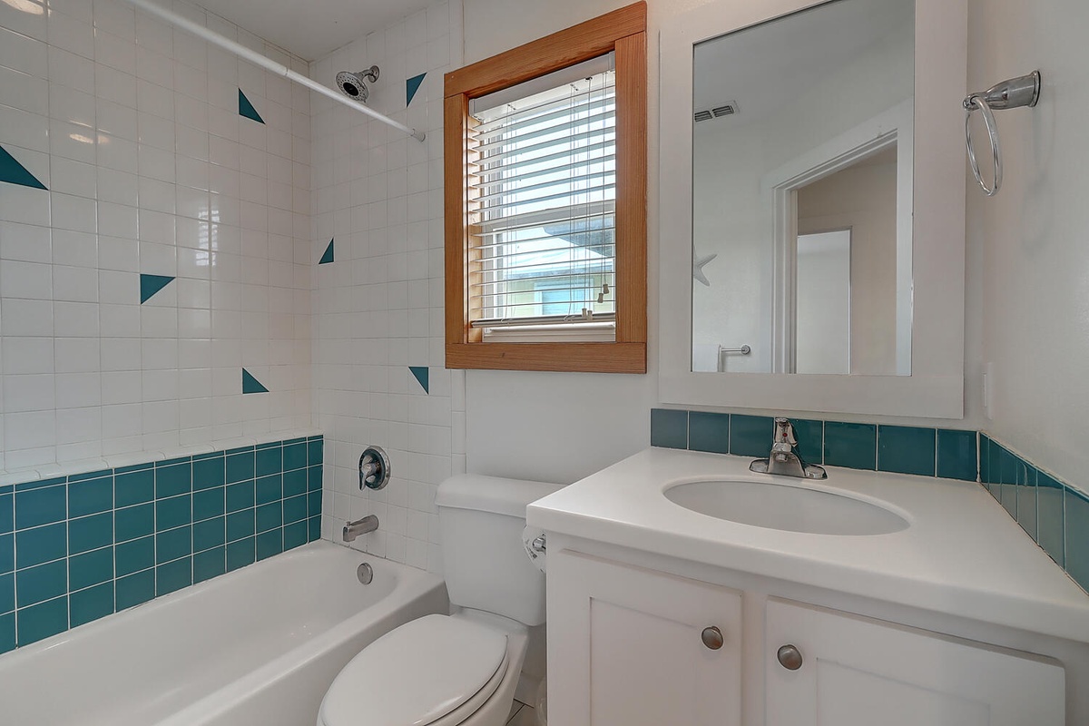 Step into your bright, cheerfully tiled bathroom where playful teal accents and natural light create a refreshing space for your daily routine.