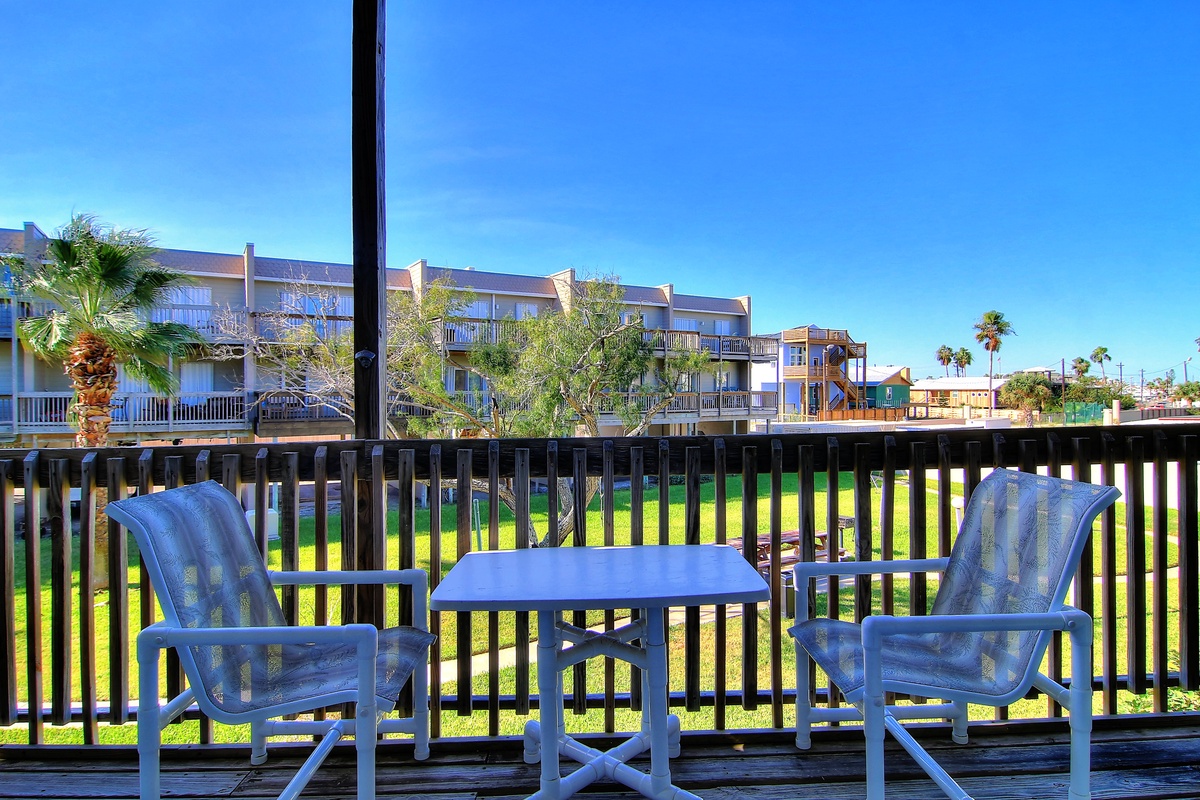 Relax on your private balcony with outdoor seating overlooking lush green grounds and nearby resort buildings.