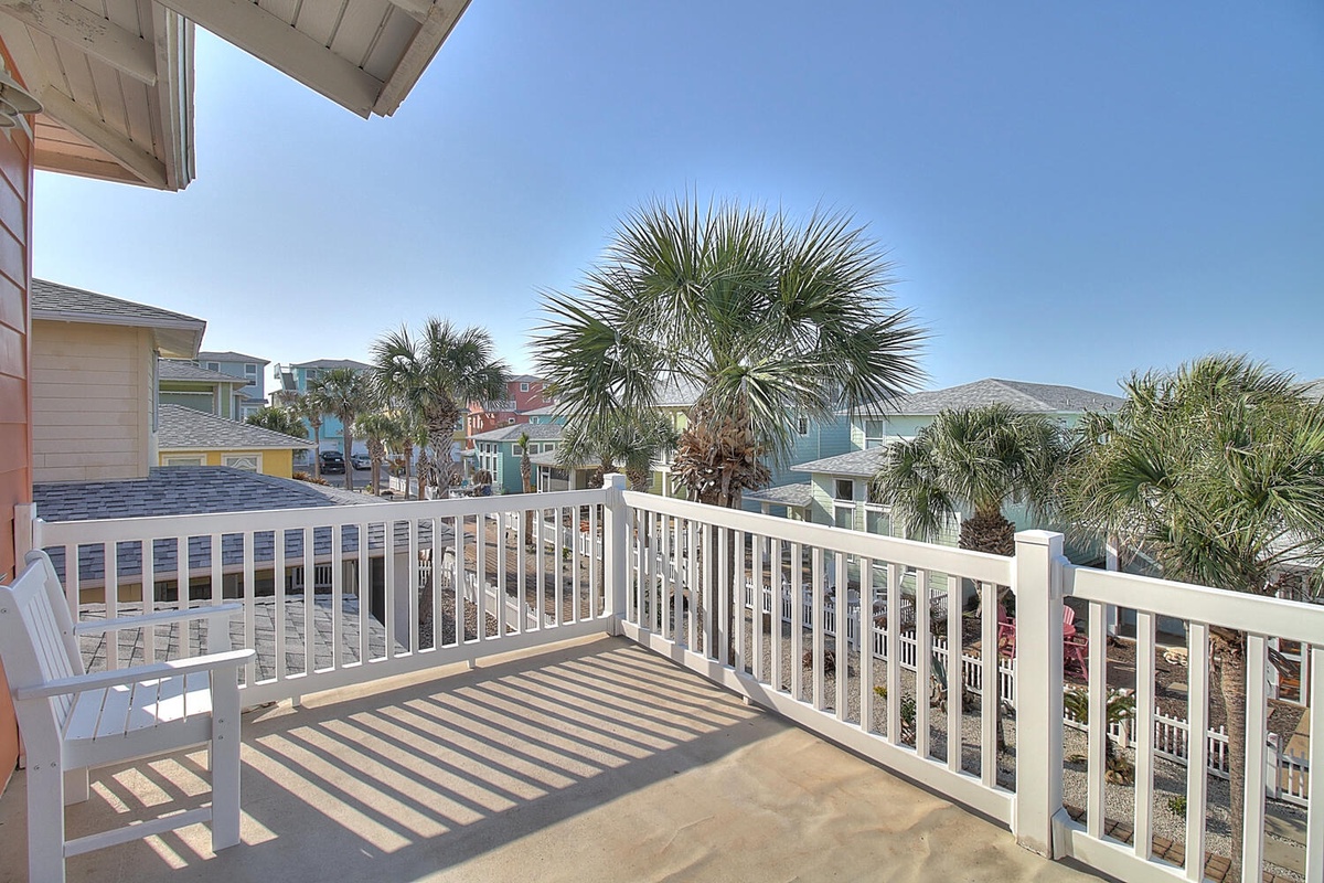 Bright coastal balcony overlooking tropical palms and colorful beach houses, perfect for morning coffee or sunset cocktails.